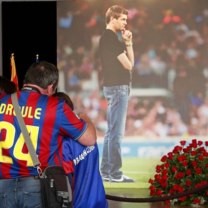 A family hugs each other in front of a picture of former Barcelona coach Francesc 'Tito' Vilanova at the Camp Nou. Photo: EPA