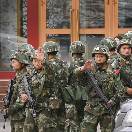 Paramilitary policemen gesture to stop a photographer from taking pictures as they stand guard after explosives attack hit downtown Urumqi on Thursday. Photo: Reuters