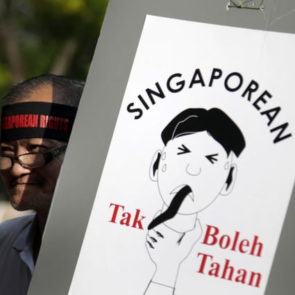 A man carries a poster which translates from the Malay language to English as "Singaporean can't take it!" as he gathers at a May Day protest in Singapore, callling for tighter curbs on the influx of foreigners. Photo: AP