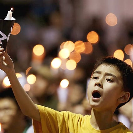A youngster holds up a candle to commemorate those who died in the Tiananmen Square crackdown at the massive rally in Victoria Park last night, which organisers said drew a record crowd. Photo: Nora Tam