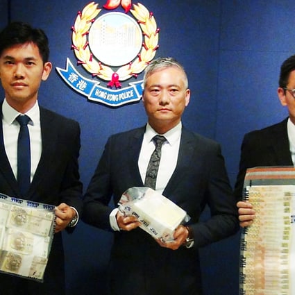 Police including Superintendent Dan Ng (centre), seized cash, luxury watches and computers in Sunday's raids. Photo: SCMP 
