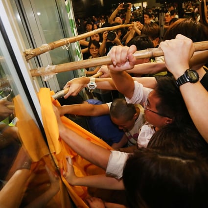 Protesters attempt to lever open the heavily guarded gates at the Legco building. Photo: SCMP