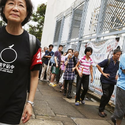An Occupy Central volunteer outside a polling station looks on as citizens line up to vote for the civil referendum. Photo: Reuters