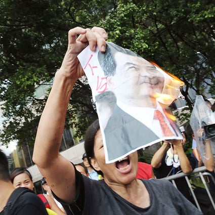 A League of Social Democrat activist calls for Chief Executive Leung Chun-ying to step down as she burns a portrait of him. Photo: David Wong