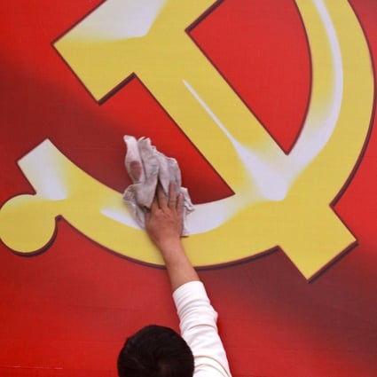 A worker wipes a board showing an emblem of Chinese Communist Party. Photo: AP