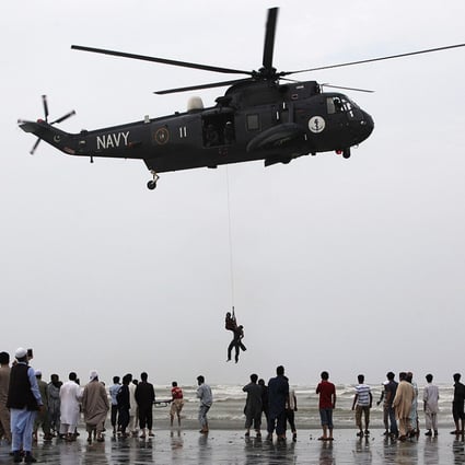 A Pakistan Navy diver hanging from a helicopter holds the body of a drowned man after recovering it from Arabian Sea off Karachi's Clifton beach. Photo: Reuters