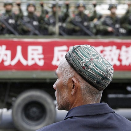 A Uyghur man looks on as a truck carrying paramilitary policemen travel along a street during an anti-terrorism oath-taking rally in Urumqi. Photo: Reuters