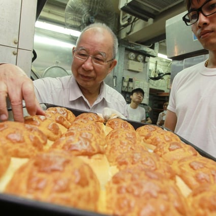 Tse Ching-yuen (left) checks out a batch of freshly baked pineapple buns at his 71-year-old Tai Tung Bakery in Yuen Long. Photo: Edward Wong