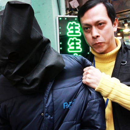 A Chinese policeman leads away a rape suspect, wearing a cloth over his head. Statistics on male rape in China are scant. Photo: David Wong