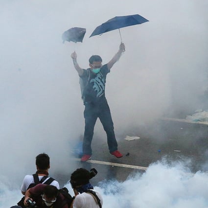 Enveloped by clouds of tear gas smoke, a protester strikes a defiant pose during yesterday's stand-off near the government headquarters in Admiralty. Photo: K.Y. Cheng