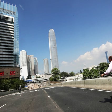 Pedestrians enjoy fresher air and a clear blue sky as they make their way along empty Connaught Road in Central yesterday. Photo: Felix Wong