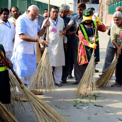 Prime Minister Narendra Modi (left) sweeps a street in a poor area of New Delhi yesterday as part of the national clean-up. Photo: AFP