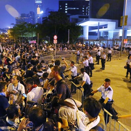 Hundreds of young protesters sit, sleep or stand outside the Chief Executive's office in Admiralty as policemen stand guard behind barriers. Photo: Felix Wong
