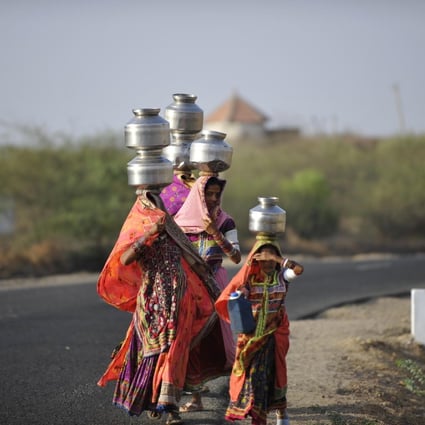 Tribal women balance steel pots of water on their heads in Banni, in Gujarat state, India.