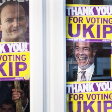 Ukip leader Nigel Farage in triumphant laughter as he glances out from behind the window of his party's campaign headquarters in Clacton yesterday. Photo: AP