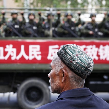 A Uygur man looks on as a truck carrying paramilitary policemen travels along a street during an anti-terrorism oath-taking rally in Urumqi. Photo: Reuters