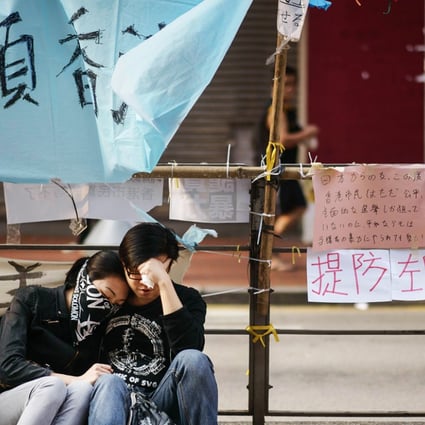 Pro-democracy protesters sit together on a kerb after police removed most of the barricades surrounding the area they were occupying in the Causeway Bay on Tuesday. Photo: AFP