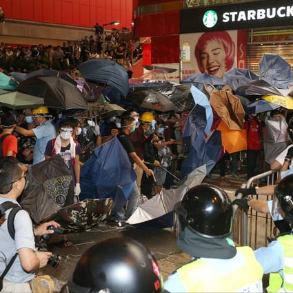 Demonstrators carrying umbrellas clash with police in Mong Kok last night, just hours after officers cleared the protest site. Photo: K.Y. Cheng