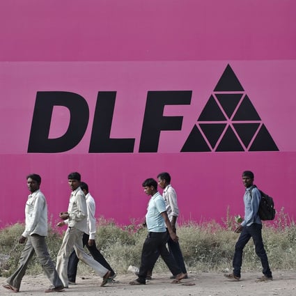 Workers walking past a billboard of DLF Ltd. at Gurgaon on the outskirts of New Delhi. Photo: Reuters