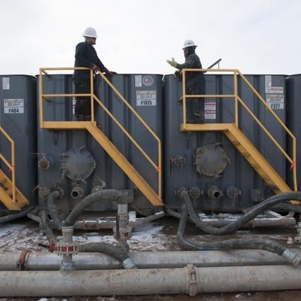 Workers monitor water tanks at a fracking site in North Dakota.