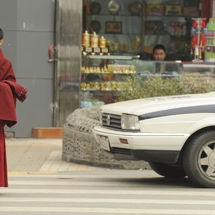 A Tibetan monk walks past a police car on a street in Chengdu, Sichuan province in this file picture from January 2012. Photo: AFP