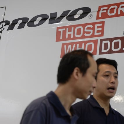 Two men walk past a Lenovo ad in Hong Kong as a report said China is poised to record the second fastest growth in the global information technology  market. Photo: AFP 