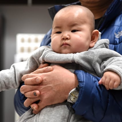 A Chinese baby in the arms of his father at a furniture store in Beijing. Photo: AFP