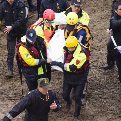 Workers carry a body away from the crash site. Photo: AFP