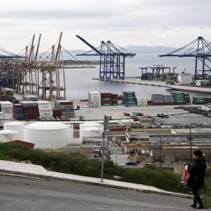 A woman walks by as Piraeus Port is seen in background, near Athens. Photo: Reuters