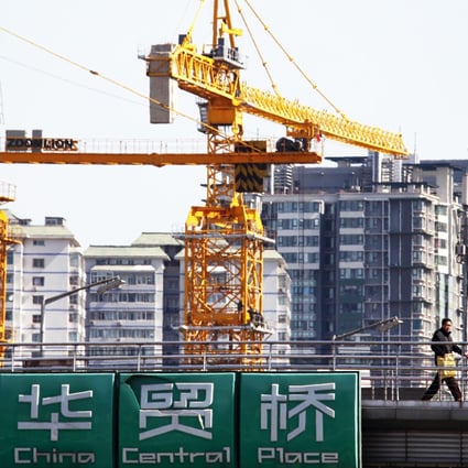 Pedestrians walk past cranes and residential buildings standing under construction in Beijing. Photo: Bloomberg