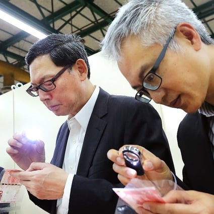Monetary Authority chief Norman Chan (centre) and executive director monetary management Howard Lee inspect notes. Photo: SCMP