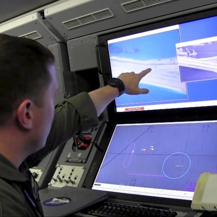 A US Navy crewman (above) aboard a P-8A Poseidon spy plane views a computer screen showing Chinese construction on the reclaimed land of Yongshu, or Fiery Cross Reef, in the disputed Spratly Islands. Photo: Reuters