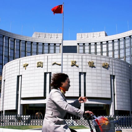 A woman rides past the headquarters of the People's Bank of China. The bank wants to find a way to lower the costs of borrowing. Photo: Reuters