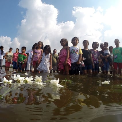 Survivors of Typhoon Haiyan put flowers into the sea as they commemorated the first anniversary of the disaster last year. Photo: Xinhua