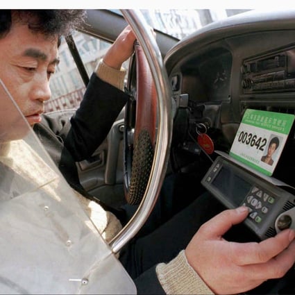 A Shanghai cab driver works on his GPS machine as taxis complain about the competition from outfits like Uber. Photo: Reuters