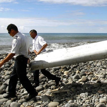 French gendarmes and police carry a large piece of plane debris which was found on the beach in Saint-Andre. It was supposedly headed for a testing centre in Toulouse, France, last night. Photo: EPA