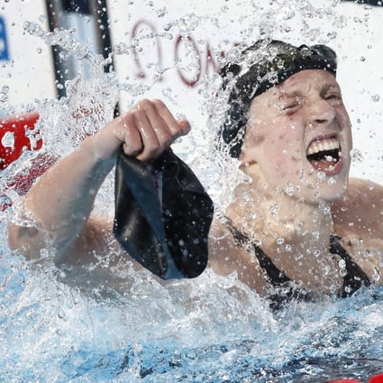 Katie Ledecky pulls off one of her swim caps after winning her fifth gold and clocking a world record in the women's 800m freestyle final. Photo: EPA