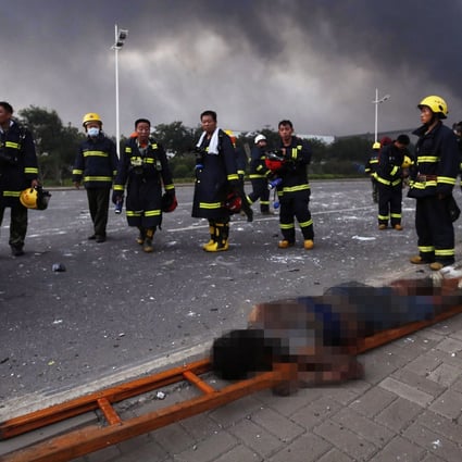 Firefighters in Tianjin walk past a victim of last night's explosions. Photo: EPA