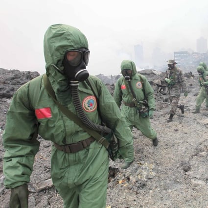 Troops in biochemical safety gear search the blast site yesterday.Photo: Xinhua