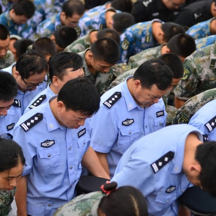 Soldiers, police officers and paramilitary policy bow their heads at a ceremony on Tuesday to mourn the victims of Tianjin's explosions. Photo: Xinhua