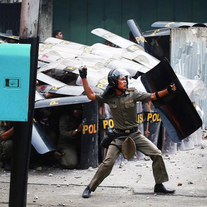 A municipal police officer throws a stone back at protesters after clashes erupted during an eviction in Jakarta, Indonesia. Photo: Reuters