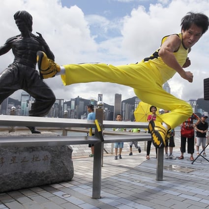 Tourists look on as a Chinese actor mirrors the fighting skills of film icon Bruce Lee at the Avenue of Stars, which offers great views of the Hong Kong skyline. Photo: Samantha SinPhoto: Edward Wong
