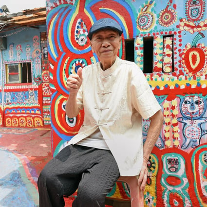 Huang Yung-fu posing for a photo next to his artwork in the Rainbow Village. Photo: AFP