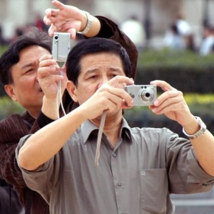 Chinese tourists take photographs during a visit to Paris.  Their reputation for carrying large amounts of cash has made them a target of thieves. File photo: Bloomberg