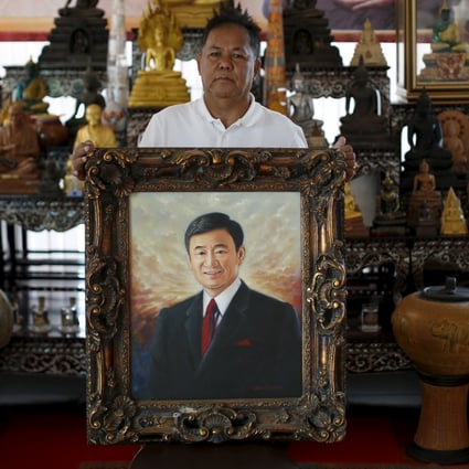 Red shirt movement leader Kwanchai Praipana poses with a photo of former PM Thaksin Shinawatra at his office in Udon Thani, Thailand. Photo: Reuters
