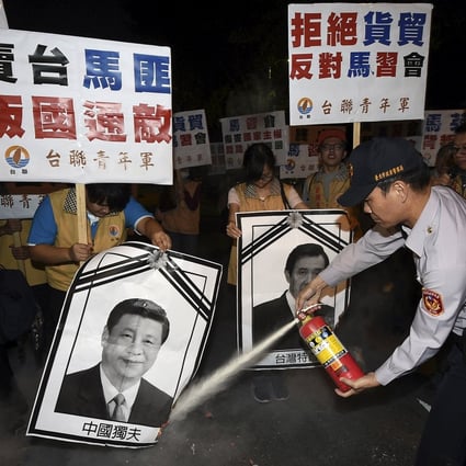 A police officer puts out fire on the portraits of Chinese President Xi Jinping and Taiwan's President Ma Ying-jeou (right) during a protest against the upcoming Singapore meeting between Ma and Xi, outside Taipei Songshan airport on Saturday. Photo: Reuters