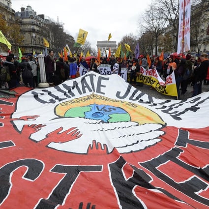 Activists hold up a giant banner calling for "climate justice" during a demonstration near the Arc de Triomphe in Paris. Photo: AFP