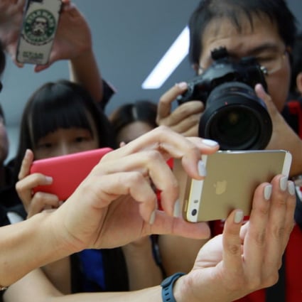 An Apple Store saleswoman holds a gold iPhone in Beijing on September 11, 2013. (Picture: SCMP)
