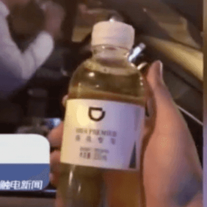 The alleged bottle of liquid gold -- and the driver, in the background, sipping his own bottle of water. (Picture: itouchtv.cn via Pear Video)
