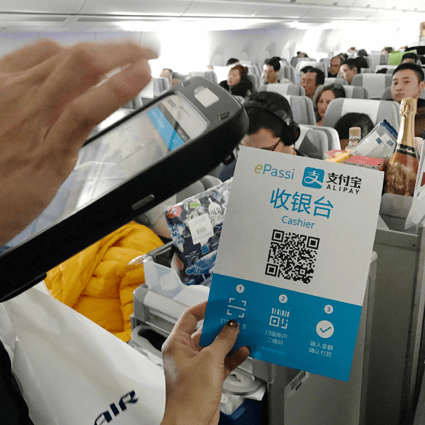 A customer scanning an Alipay payment code held by a flight attendant on a plane bound for Helsinki from Beijing. (Picture: Zhang Xuan/Xinhua)